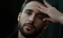a man holding his hand up to his head
