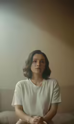 a woman in white shirt sitting on a bed