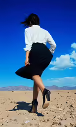 there is a woman walking in the desert wearing a skirt