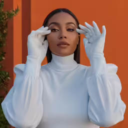 the model in a white top is holding her hands to her temples
