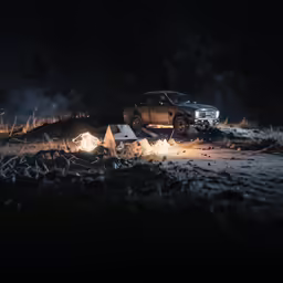 a truck on the ground in the dark by a campfire