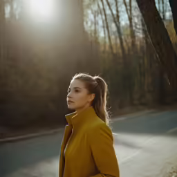 a woman standing in the middle of a road with trees in the background