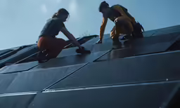 two people standing on a ledge with rain falling
