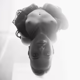 a woman with her eyes closed and a lacy bra, looking down from her high dive