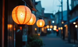 illuminated lanterns hanging off the side of buildings on a street