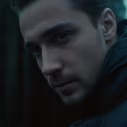 a man in a hooded jacket stares into the camera