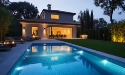 a swimming pool at night with lawn furniture near by