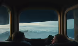 two people in train looking out the window of a snowy landscape