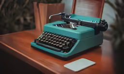 a blue typewriter sitting on a table with its case open