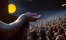 a hand that is reaching towards something with a crowd of people in the background