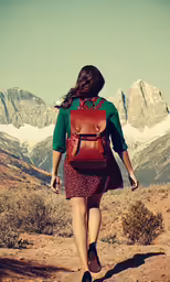 a woman walking away from the camera wearing a brown backpack