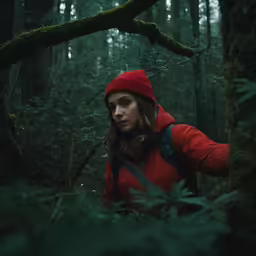 a woman is standing among plants in the forest