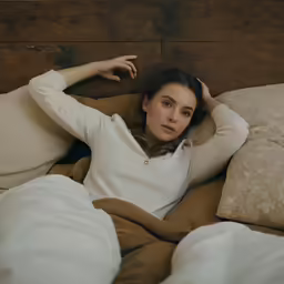 a woman lying in bed with her hand on her head