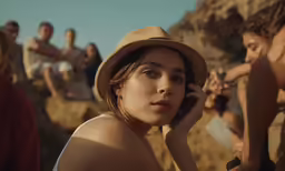 a young girl in a hat sits next to other people