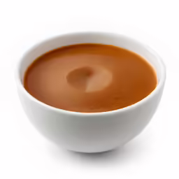 a cup filled with soup sitting on top of a white table