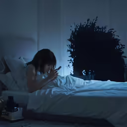 a person that is sitting on a bed in the dark