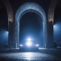 a vehicle parked in front of an archway at night