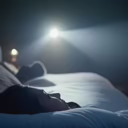 the woman is laying down on her bed in the dark