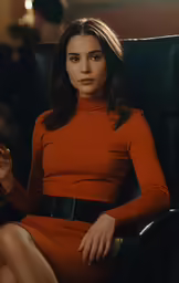 a woman sitting in a black chair wearing an orange dress