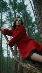 woman in red shirt posing on a rope swing in the woods