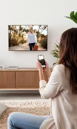 a woman is on her television with a remote