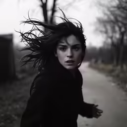 a woman in black coat and hair blowing