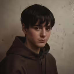 a young boy poses in front of a neutral background