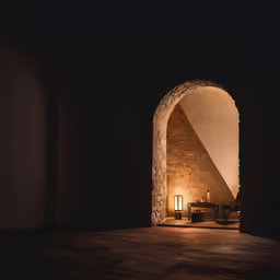dark room lit up with light shining through an arch