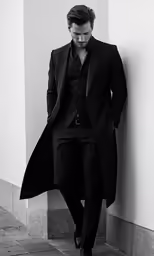 the man in a suit is leaning against a wall