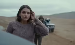 the person standing beside the truck is talking on a cell phone
