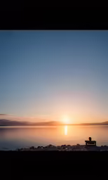 a bench in front of the sun on top of water