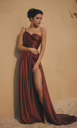 a woman in a brown dress standing against a wall