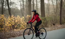 a woman riding a bike down a road in the woods