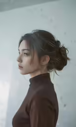 woman in brown shirt facing off to the side with hair pinned into updo