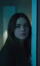 the girl is standing behind a wall, with her head down and arms resting on the edge of her chest
