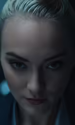a young lady wearing a blue coat has her head shaved in ponytails