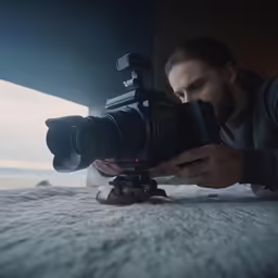 man on bed with camera on tripod looking at photos