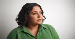 a woman wearing a green shirt looks up at something