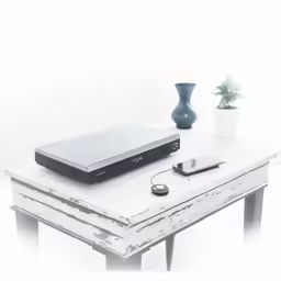 a table with a cell phone, remote control, laptop and other things