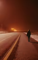 a man walking across a road with a snow covered ground