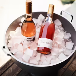 two bottles of wine in ice bucket on wooden table