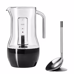 a glass pitcher with a spoon sitting next to it