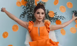 a woman in an orange dress posing for the camera