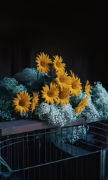 yellow and white flowers in a basket sitting on the outside fence