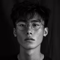 a black and white photo of a man with glasses,a man in glasses is staring away from the camera