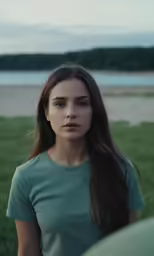 a girl standing on the grass looking at the camera