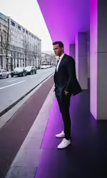 a man in a suit and sneakers is posed for a photo