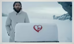man in white jacket carrying mail in the snow