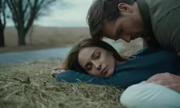 a couple cuddle together on the ground in the grass