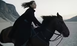 the woman is riding her horse on the beach